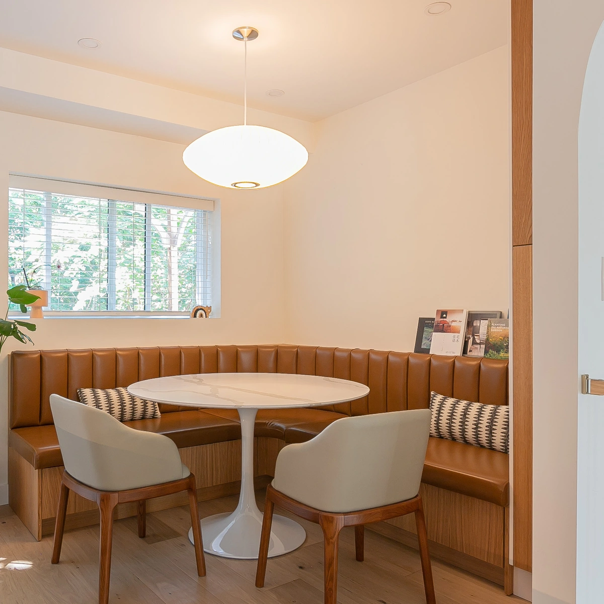 Custom banquette seating with caramel channel-stitched upholstery wrapping a round table in a breakfast nook