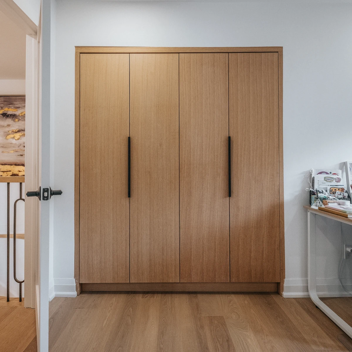 Custom built-in closet with oak doors and black handles in a bedroom