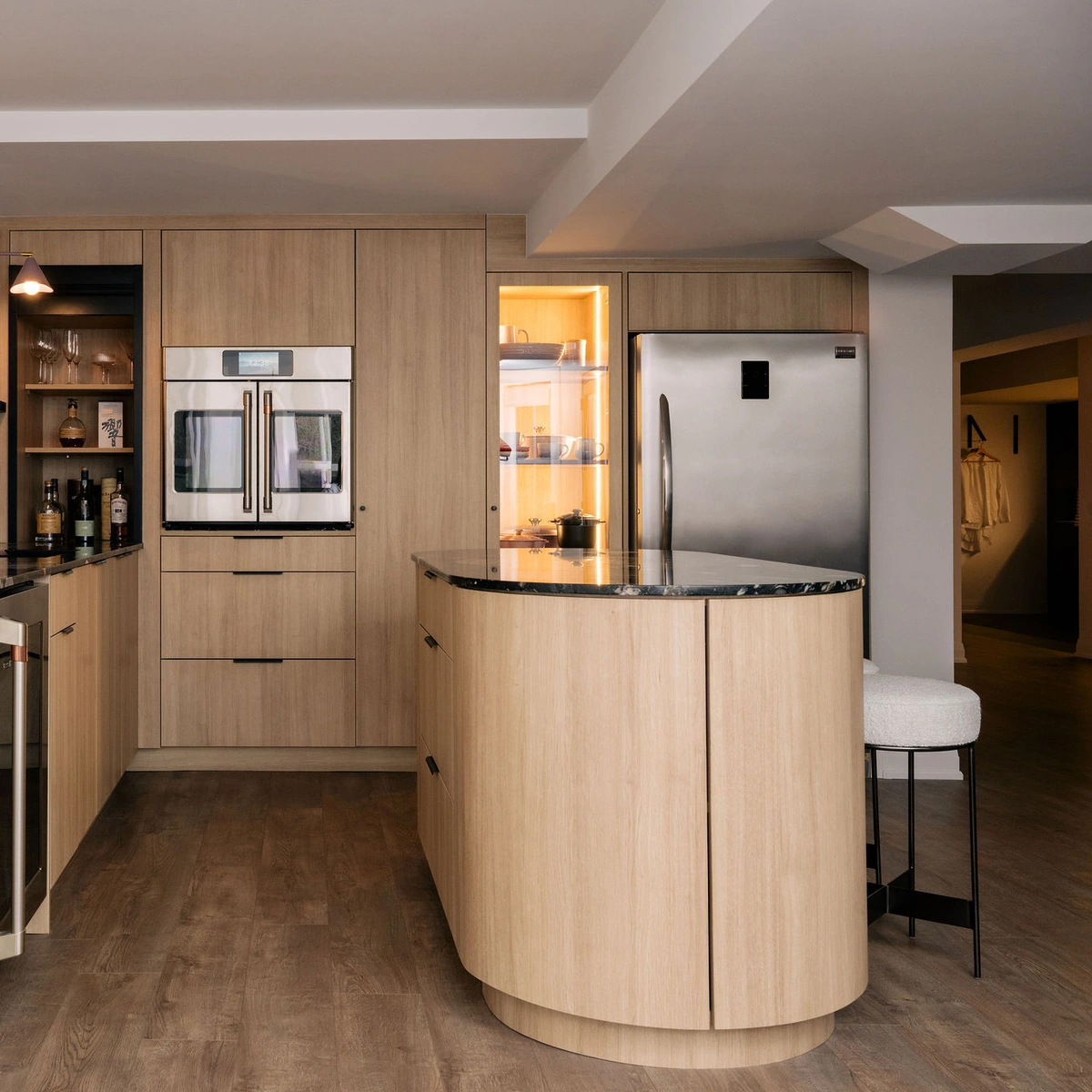Custom round kitchen island in light oak with a black stone top