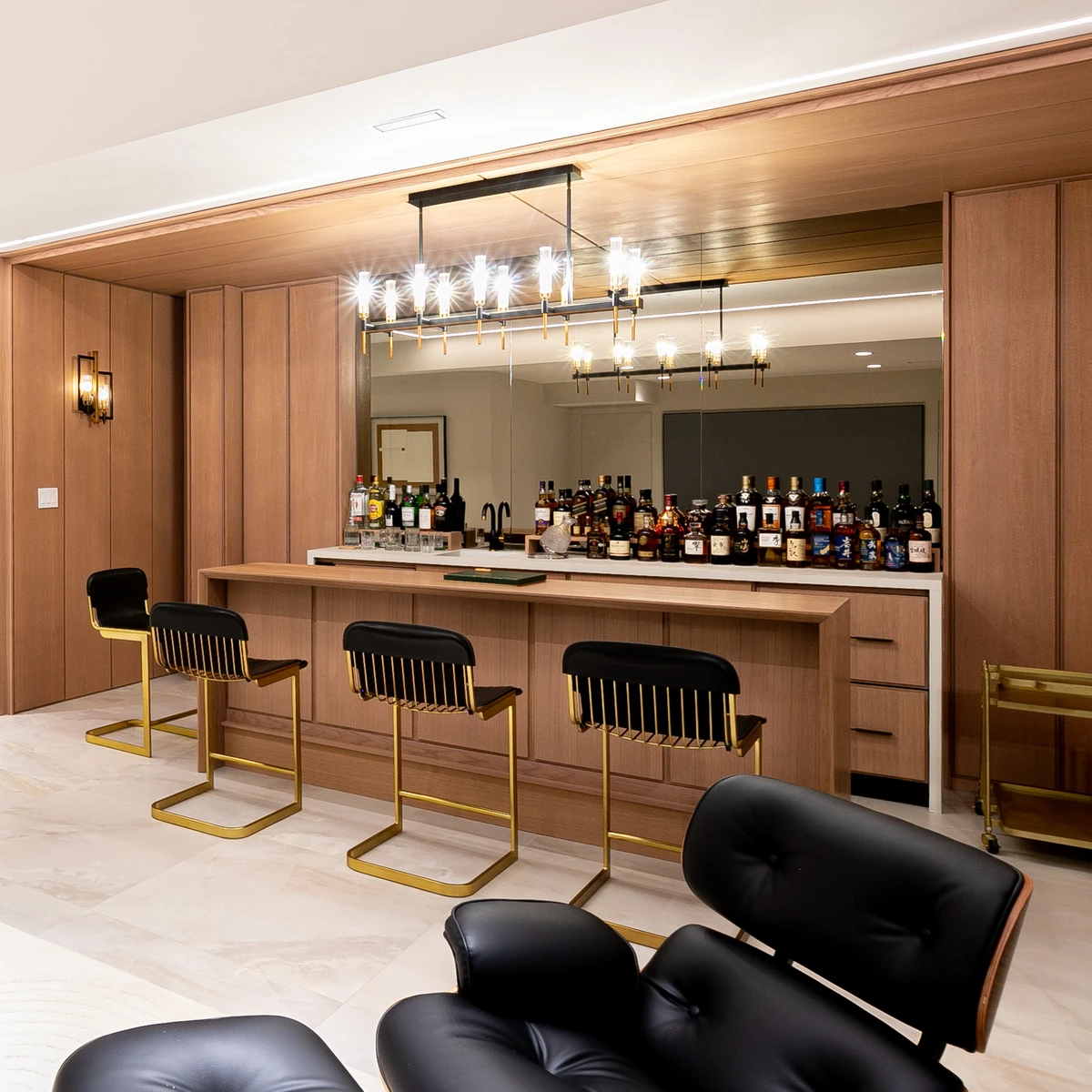 Custom wood veneer wall panels around a home bar with mirrored back wall